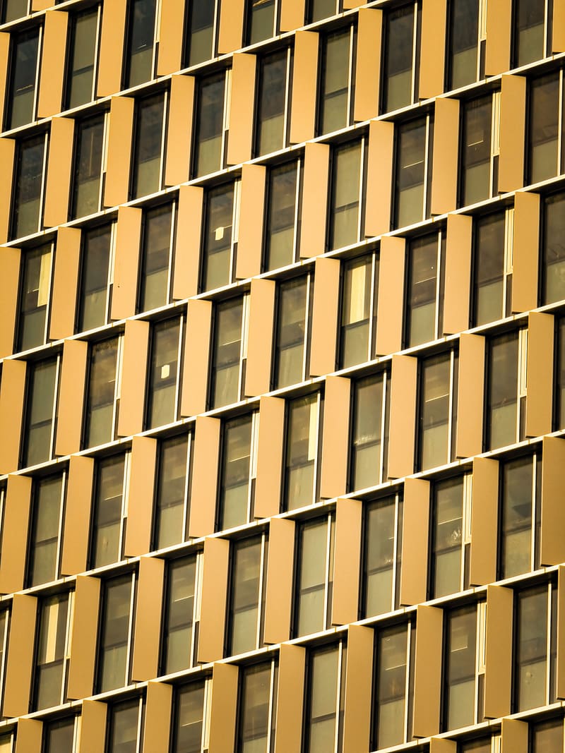 A building facade of gold-toned fins and windows repeating to the edges of the frame.
