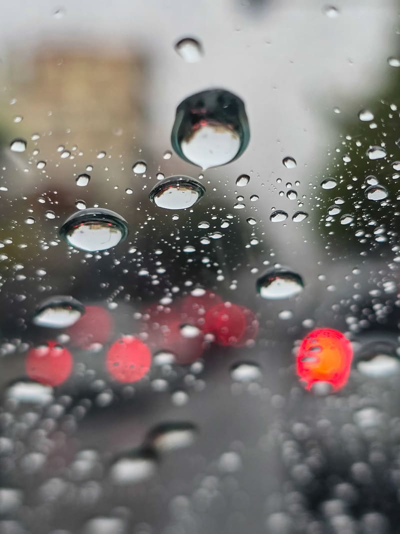 Raindrops on glass, with blurred red tail lights behind.