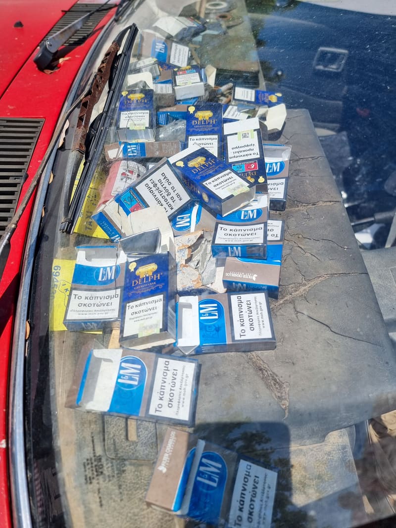 Packs of cigarettes spread out on a red car bonnet.