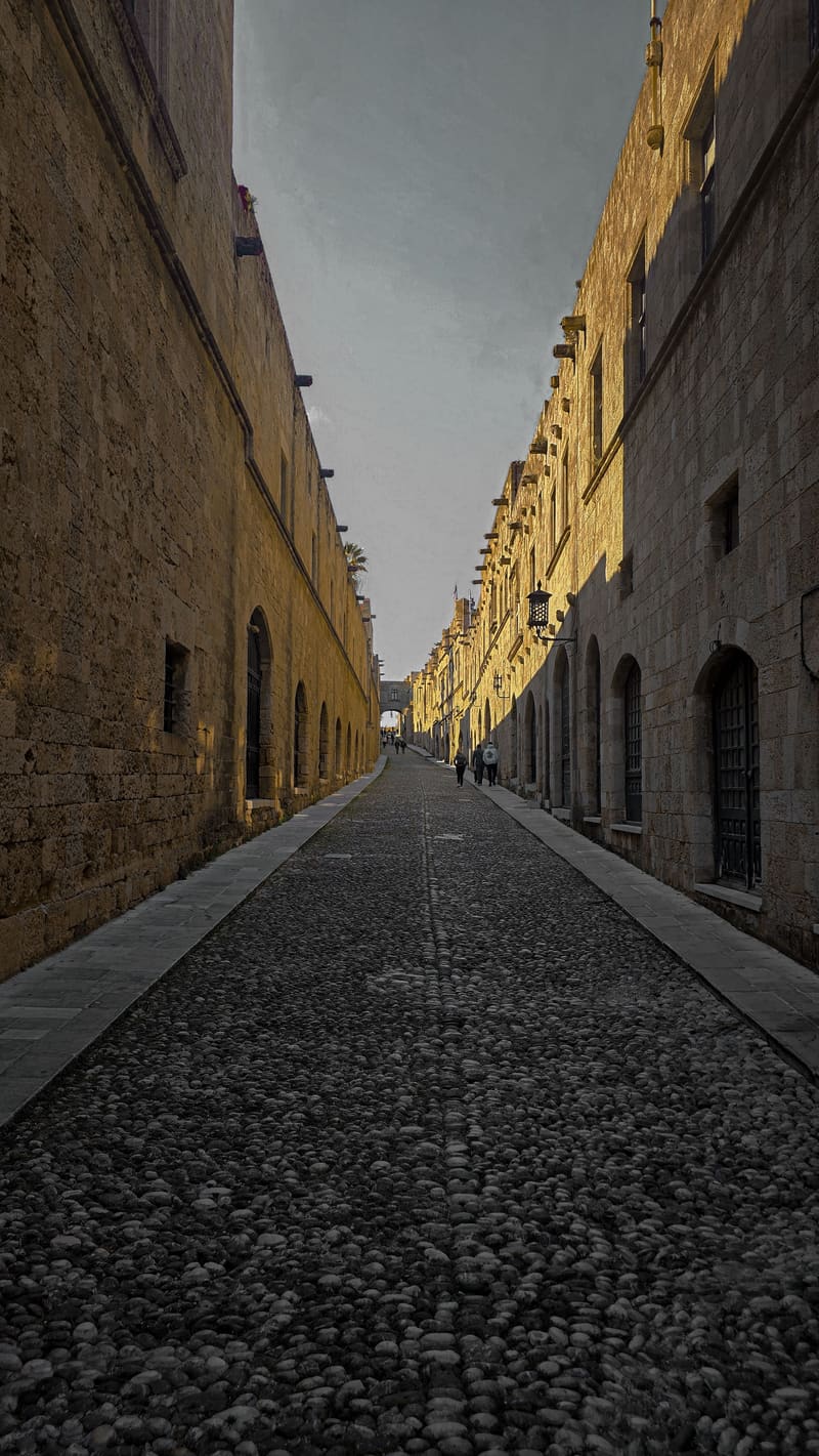 A long medieval street of stone buildings, its cobbles narrowing into the distance.