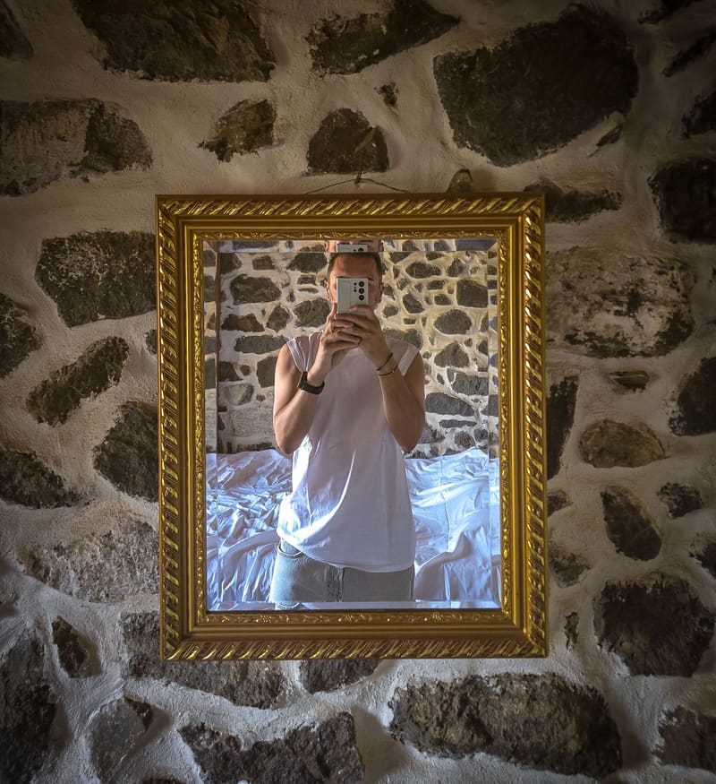 A mirror selfie in a gilded frame set into a rough stone wall.