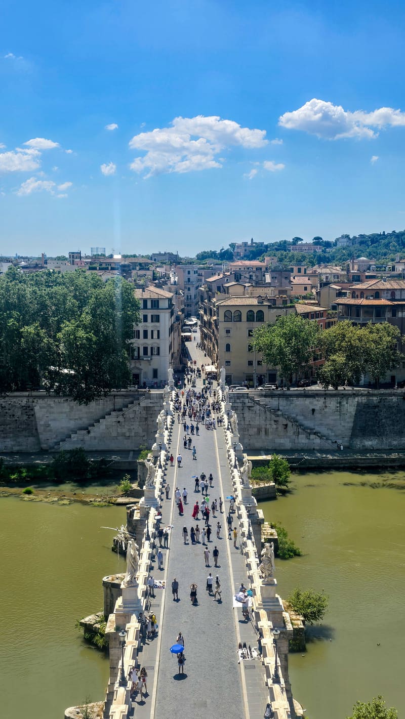 A bridge over a green river, looking toward the city under a blue sky.