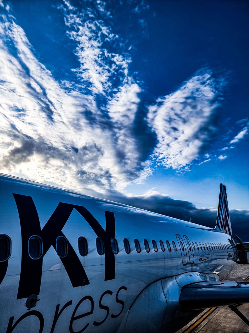 The fuselage and tail of a SKY express plane under a streaked blue sky.