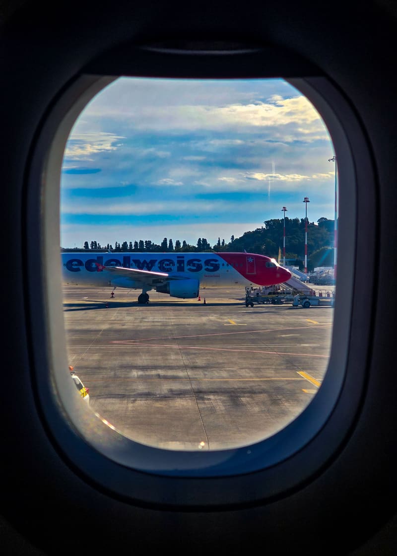 An aeroplane window framing another plane on the tarmac.