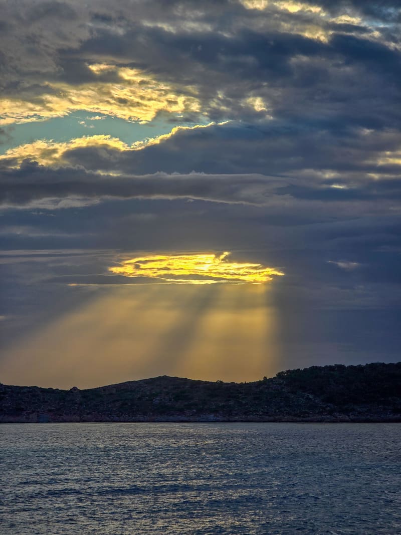 Sun rays breaking through dark clouds over the sea.