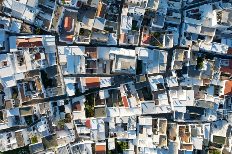 Aerial view straight down onto the flat white rooftops and narrow lanes of a dense village.