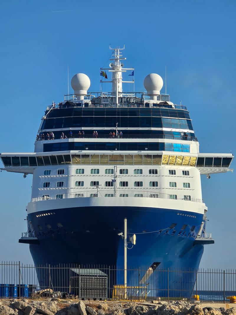 The bow of a large cruise ship in port.