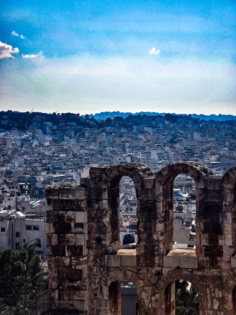 Ancient stone arches with a city spreading out behind them.