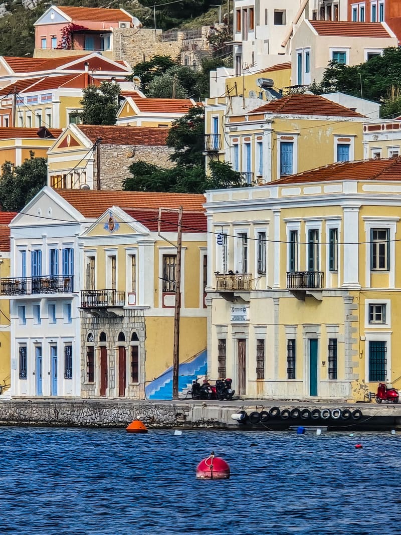 Neoclassical harbour houses in yellow and cream above the water.