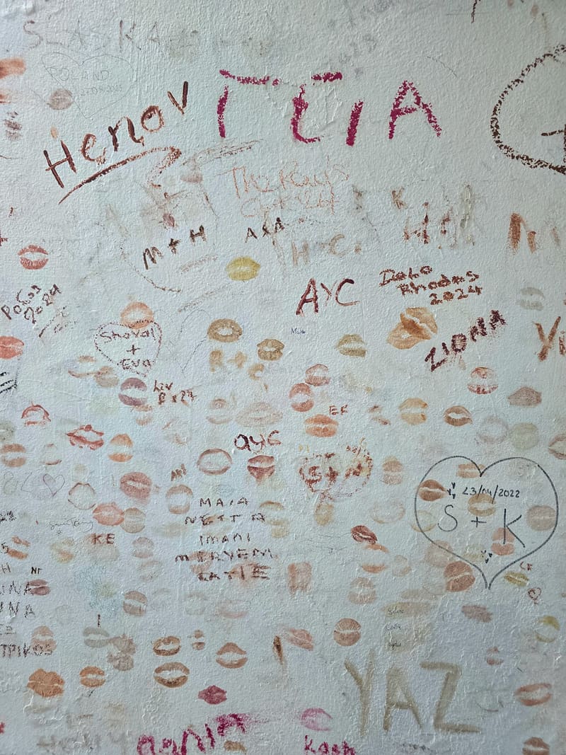 A wall covered in handwritten names and lipstick kisses.