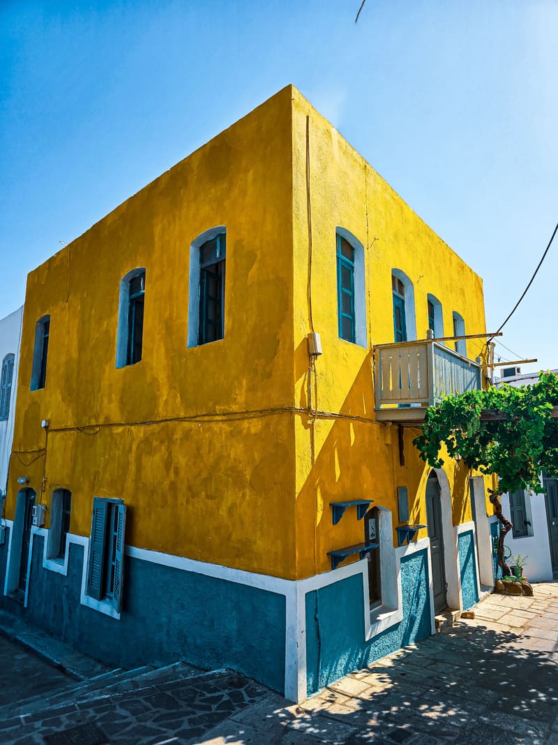 A yellow two-storey house with blue trim on a sunny corner.