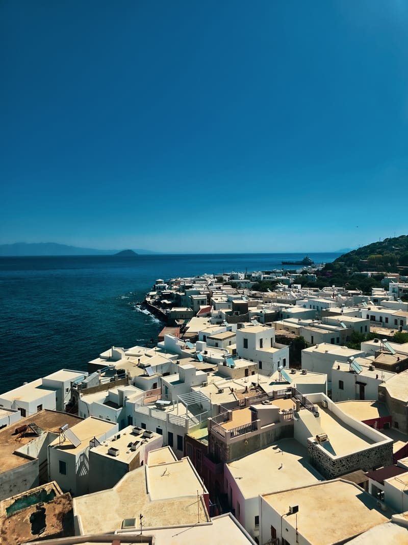 Whitewashed village rooftops above a blue sea.