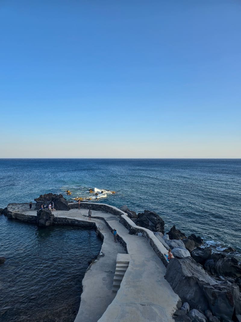 A stone jetty curving into a dark blue sea.