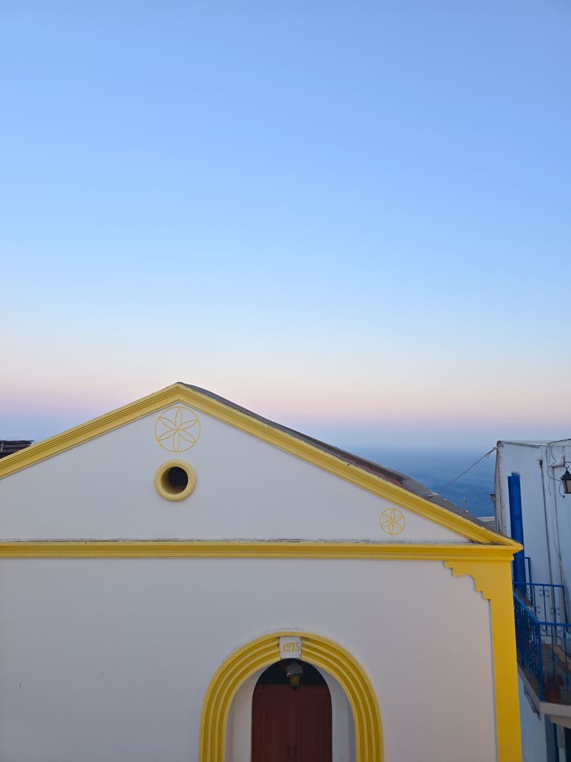 The yellow-trimmed gable of a white chapel at dusk.