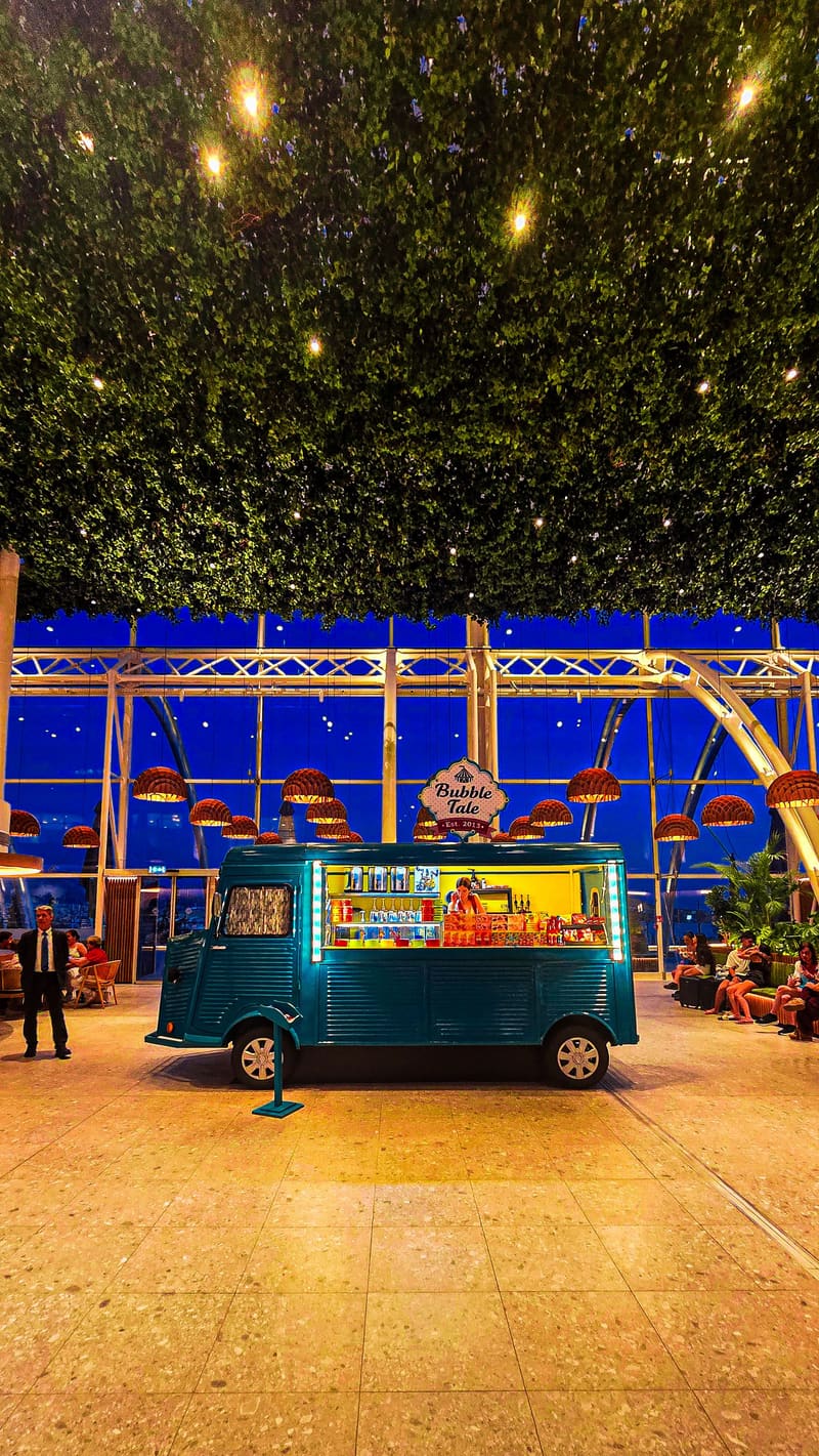 A food truck parked in a lit courtyard under hanging greenery.
