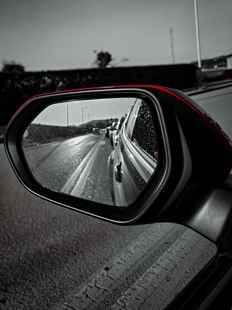 Black and white: a road reflected in a car's side mirror.